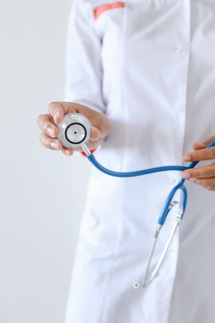 A medical professional in a white coat holding a stethoscope, highlighting healthcare and medicine.